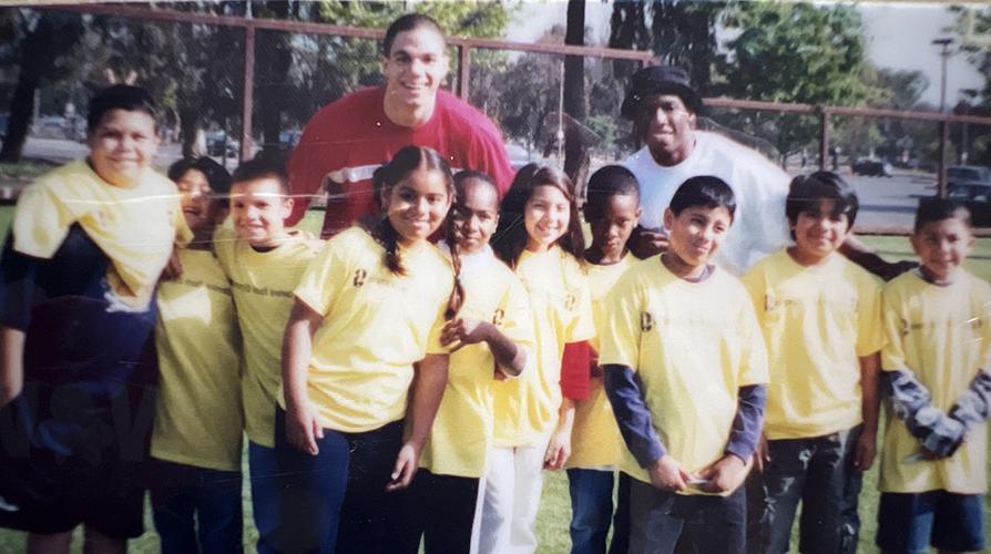 10 smiling kids in yellow t-shirts posing with two adults