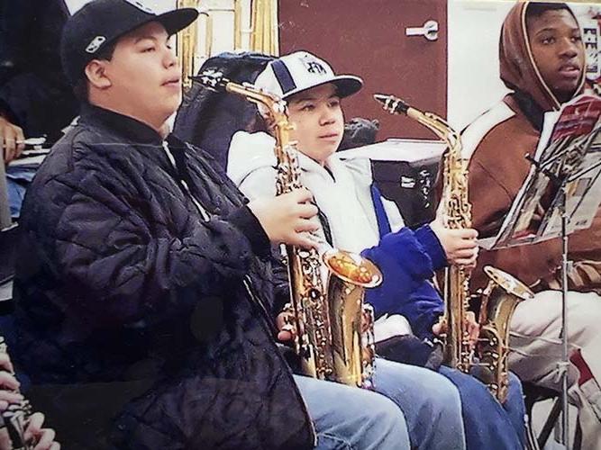 Three boys playing saxophones in the band